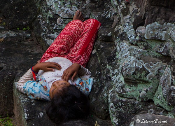 A young girl takes a break from trying to sell souvenirs to tourists.